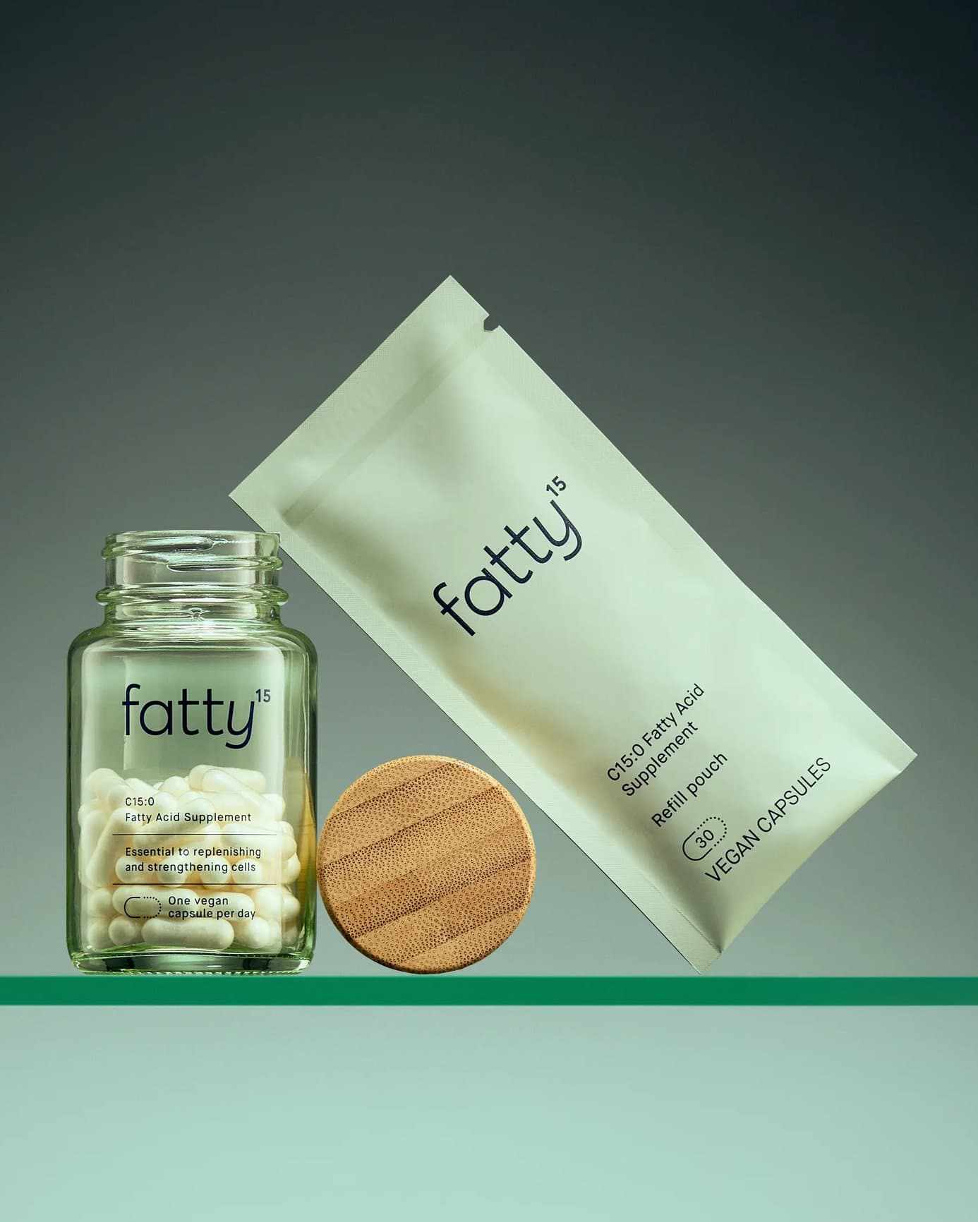 Fatty15 jar, refill pouch and bamboo lid on a glass shelf